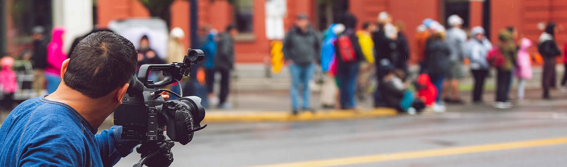 view of videographer filming crowd gathered along sidewalk