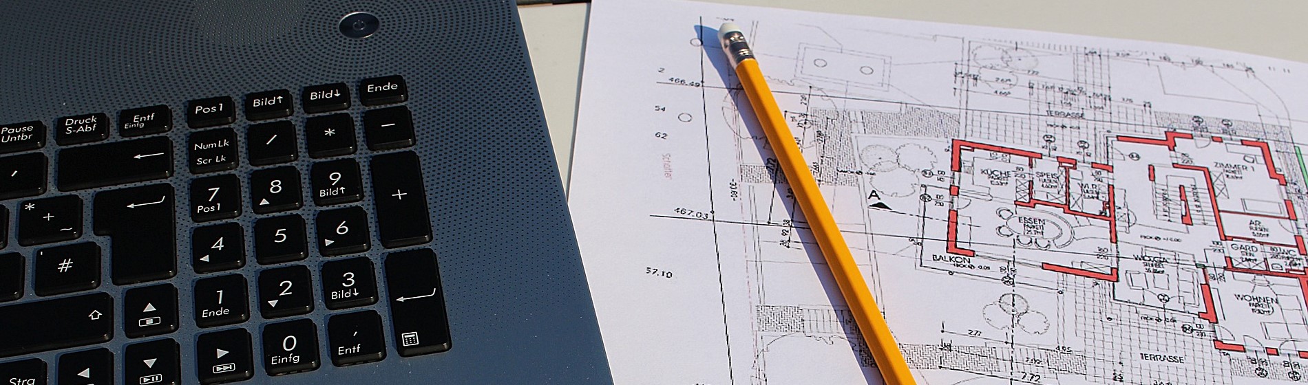 closeup of laptop, pencil and building plans