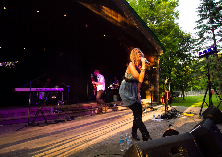 woman singing on a stage with a band behind her